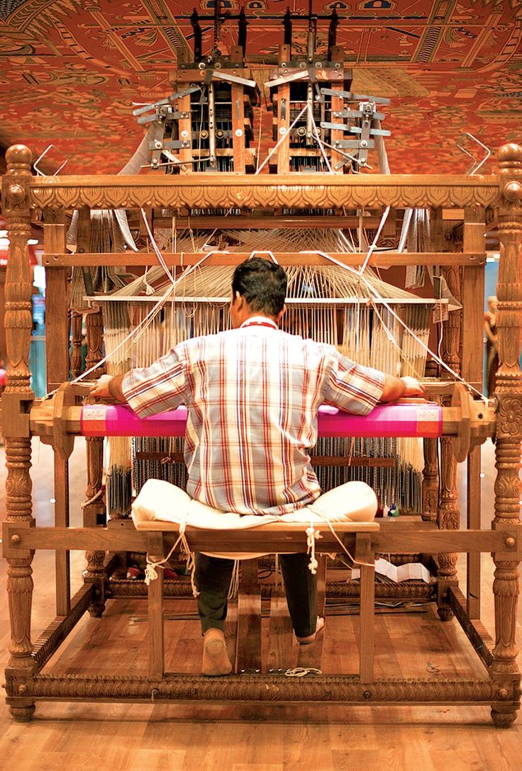 An artisan carefully working on a handwoven carpet at a loom