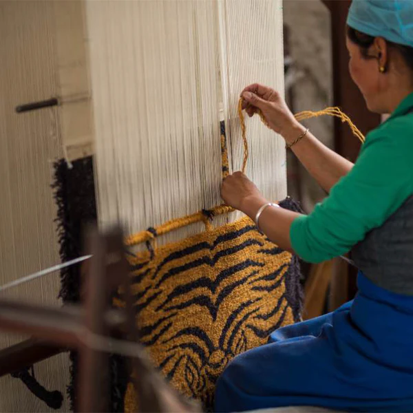 A carpet artisan weaving a patterned rug on a traditional loom